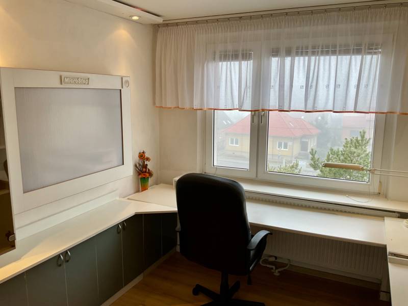 A study in a 3-room apartment with a window, a corner desk, and a floor with a wooden decor.