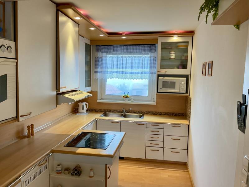 Kitchen in a 3-room apartment with white cabinets and a wood-patterned floor.