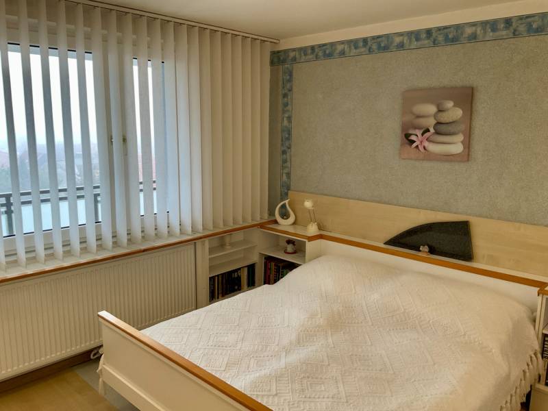 Bedroom in a 3-room apartment with a bed, vertical blinds, and a picture on the wall.