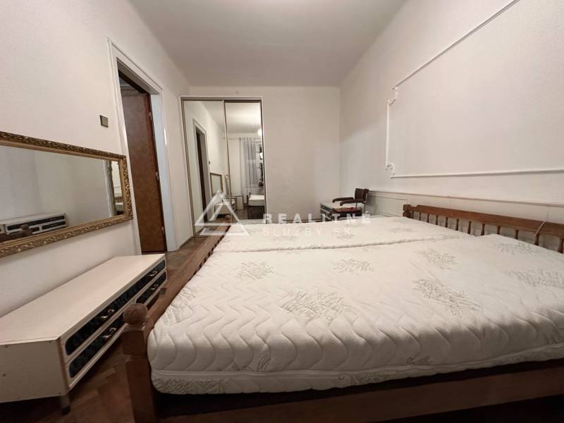 Bedroom with a bed and a mirror in a 3-room apartment, floor with wooden decor.