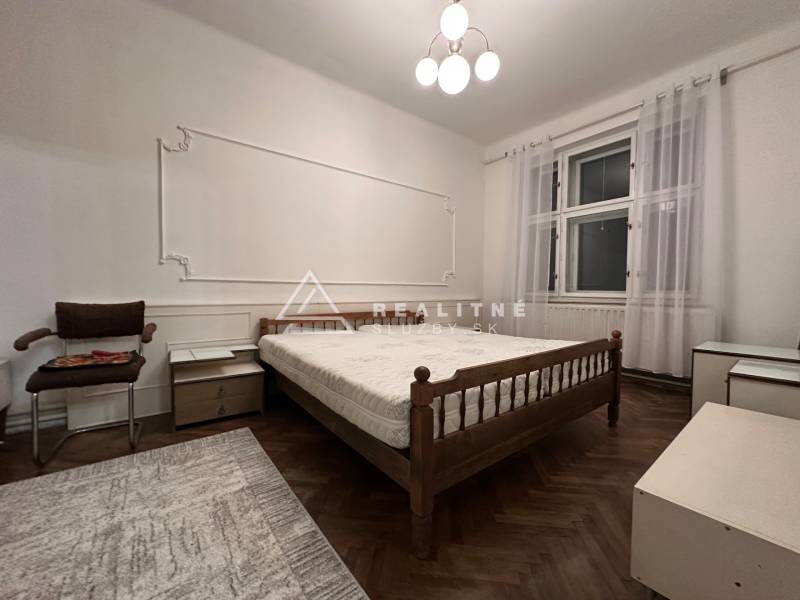 A bedroom in a 3-room apartment with a simple bed and a floor with a wood decor.