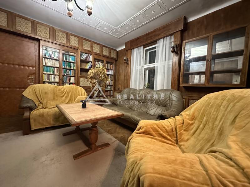 Living room in a 3-room apartment with wooden paneling, sofas, and a bookshelf.