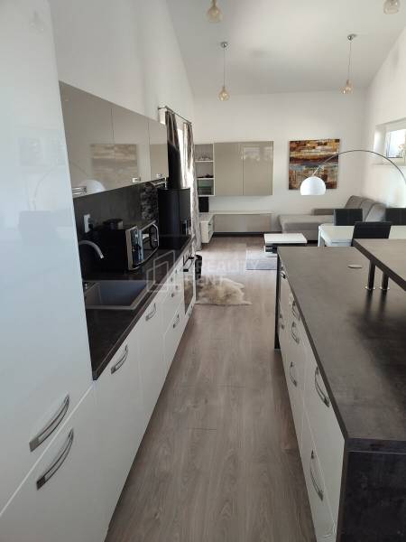 Modern kitchen with wood-patterned flooring and comfortable furniture in a family house.