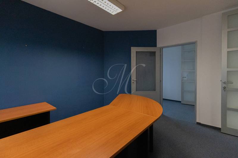 Blue and white office space with a wooden desk and glass doors in a 4-room apartment.