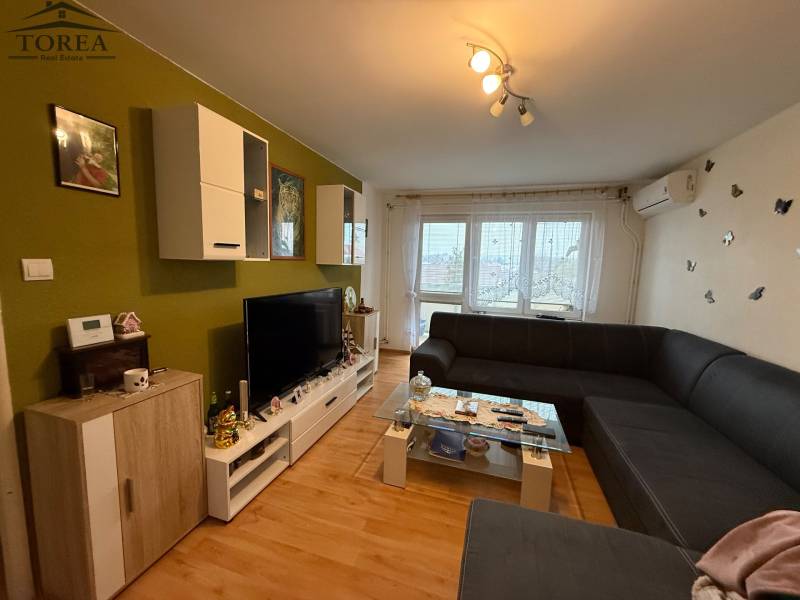 Living room in a three-room apartment with a large sofa and a floor with a wooden decor.
