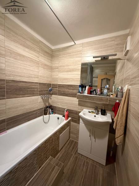 Bathroom in a 3-room apartment with a bathtub, sink, and tiles in neutral tones.