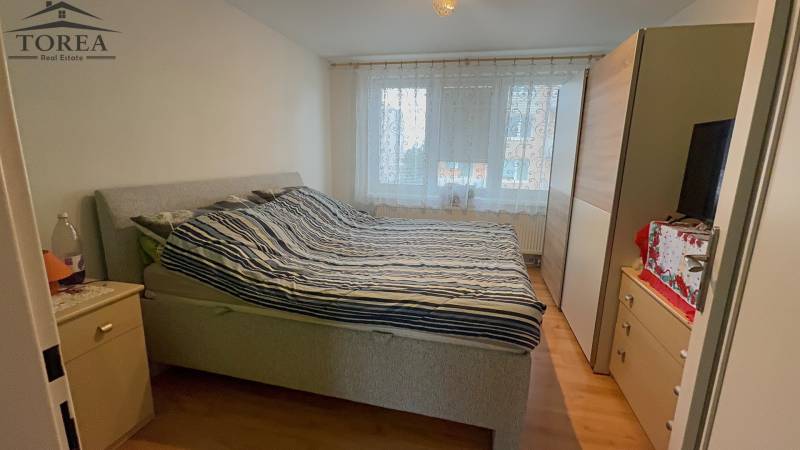 A bedroom with a large bed, a wardrobe, and a wooden decor floor in a 3-room apartment.