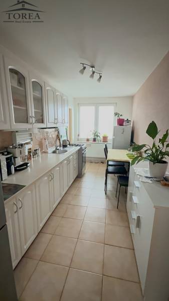 A kitchen in a 3-room apartment with light white cabinets and a dining table.