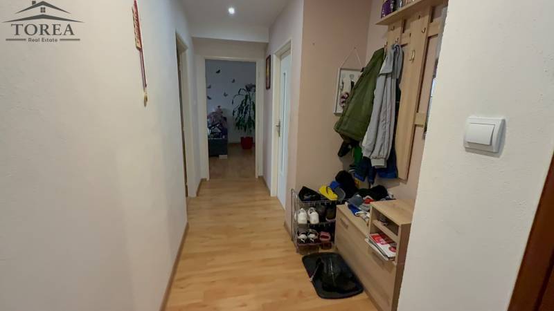 A hallway with a wooden decor floor and a wardrobe in a 3-room apartment.