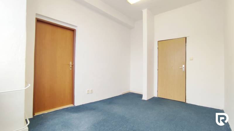 Offices with white walls and blue carpet, simple interior with two wooden doors.