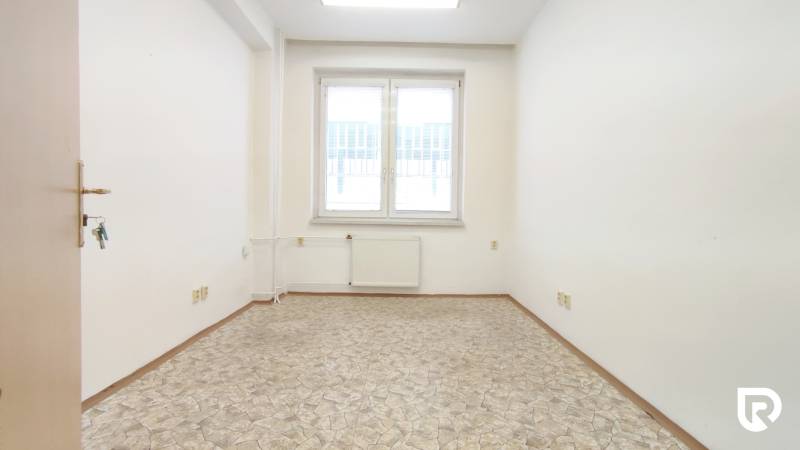 A small office with keys on the door, a window, and a light floor.