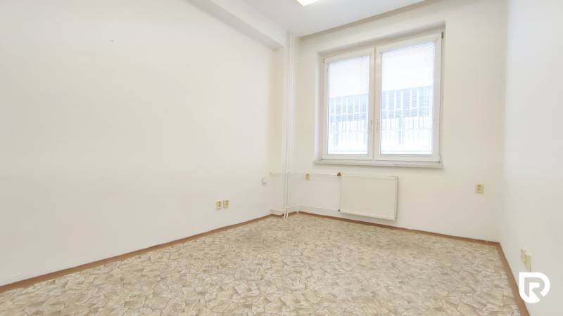Office with a window, white walls, and tiled floor.