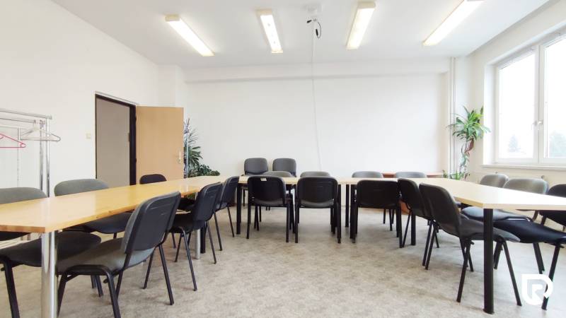 Offices with desks and chairs, bright lighting, plants, and a coat rack.