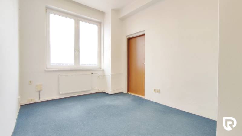 Offices with blue carpet, plain walls, and a window next to the door.