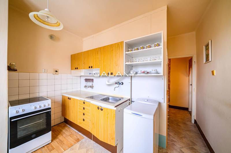 A kitchen in a 2-room apartment with a wooden decor floor and a stove.
