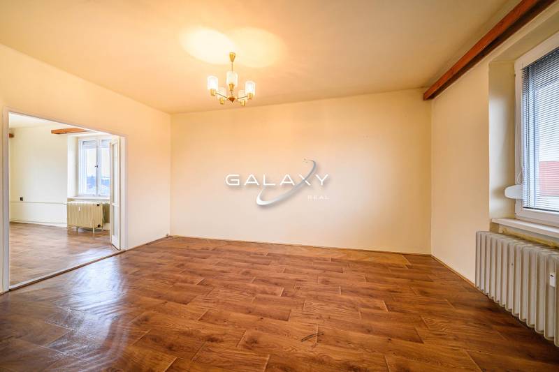Interior of a 2-room apartment with a wooden decor floor and a chandelier.