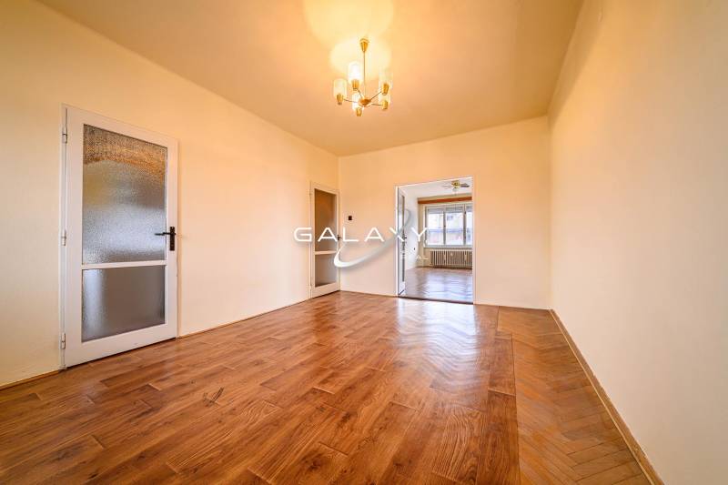 Living room in a two-room apartment with a wooden decor floor and a chandelier.
