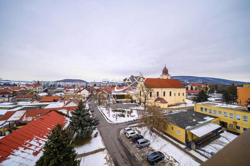 Winter landscape in Fiľakovo with a church, rooftops of houses, and snowy streets.