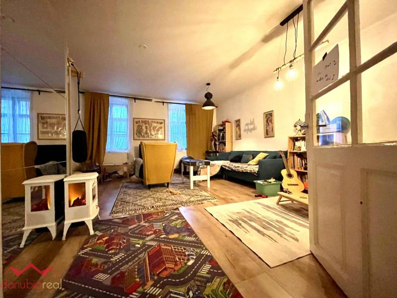 Living room with a sofa, armchairs, carpet, and wooden decor flooring in a family house.