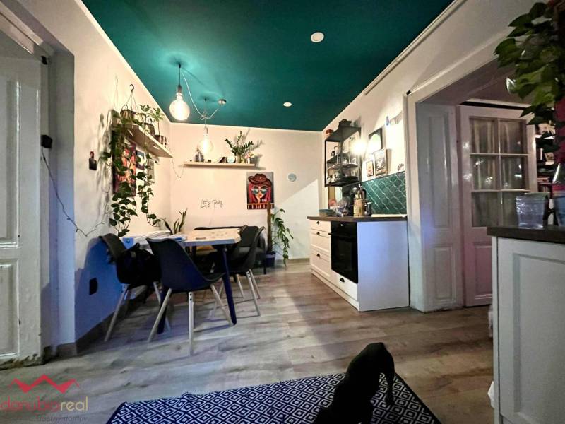 A kitchen in a family house with a wooden decor floor, a dining table, and plants.