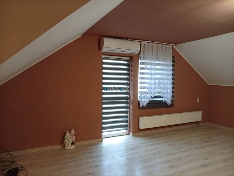 Attic room with air conditioning and wood-patterned flooring in a family house.