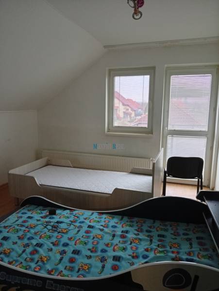Children's room in a family house with two beds and an armchair, floor with wooden decor.