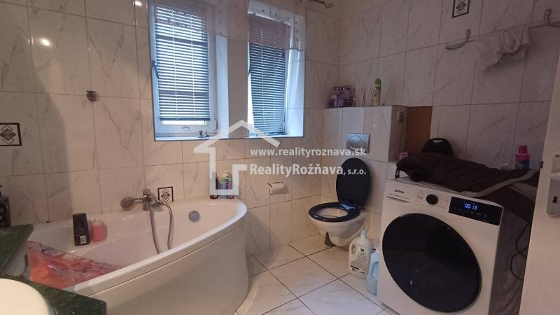 A bathroom in a 2-room apartment with a washing machine, a bathtub, and a toilet, tiled with tiles.