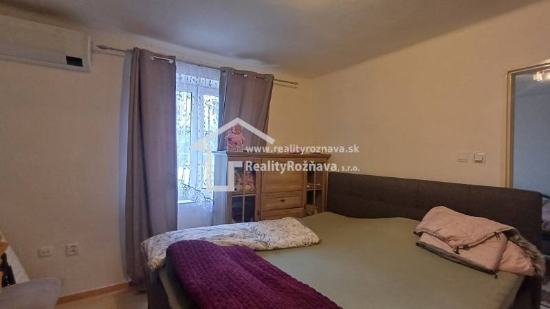 Bedroom in a 2-room apartment with a bed and a wardrobe, light curtain on the window.