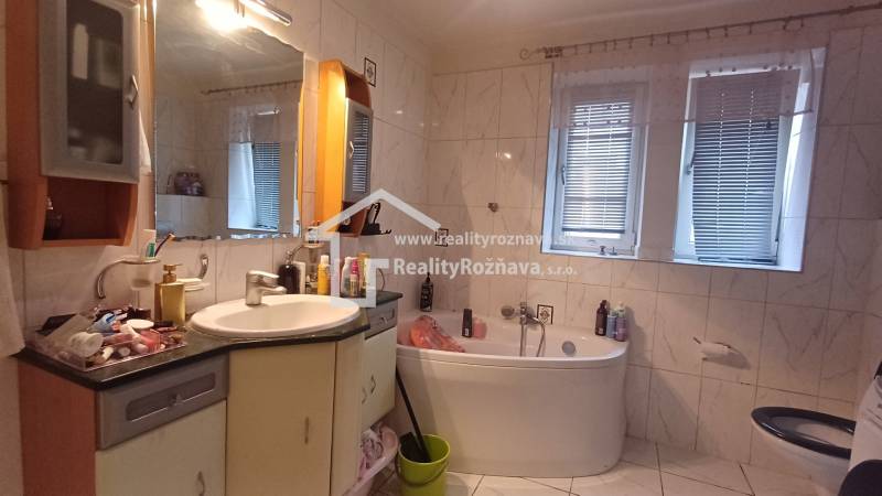 A bathroom with a bathtub, double window, and white tiles in a 2-room apartment.