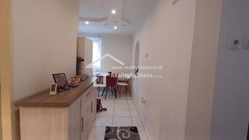 A hallway in a 2-room apartment with wooden decor and a dining table at the end.