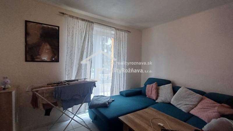 A bright living room with a sofa and a drying rack in a 2-room apartment.