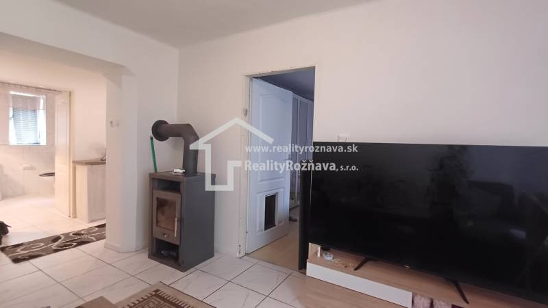 Interior of a 2-room apartment with a stove, television, and floor with wood decor.