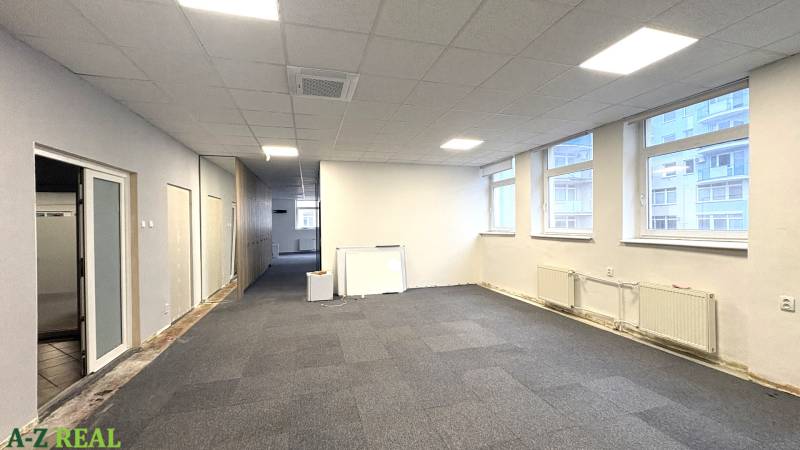 Offices with carpeted floors, large windows, white walls, mirror on the wall.