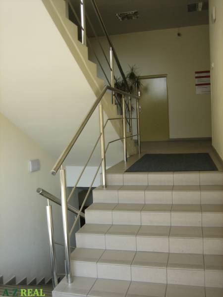 A staircase with stainless steel railing leads to offices with tiling.