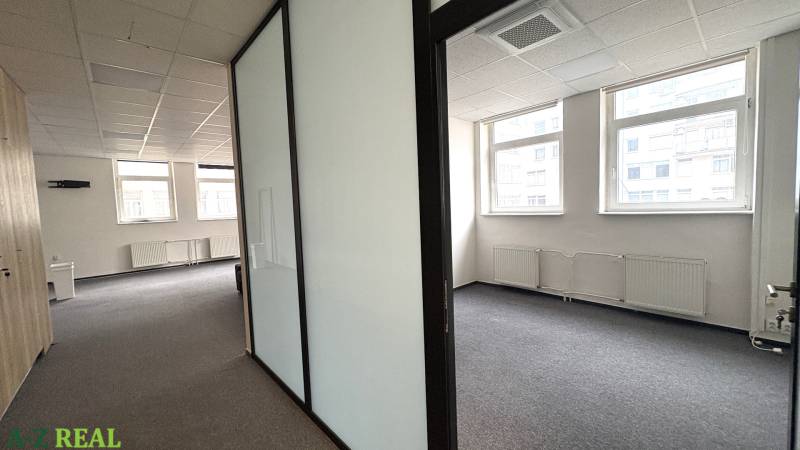 Offices with white walls, a glass partition, and large windows; carpeted floor.