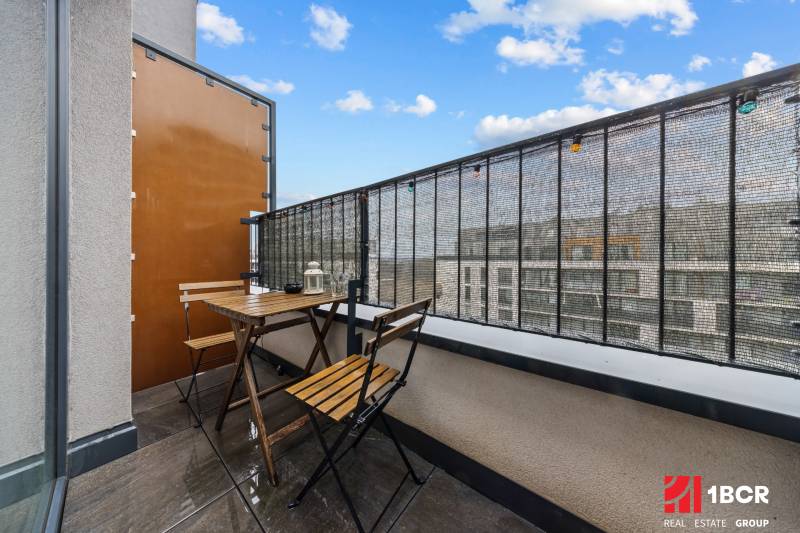 The balcony of a one-room apartment on Zuzany Chalupovej in Bratislava - Petržalka, with wooden seating.