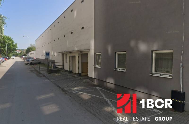Garages on Laco Novomeský Street in Pezinok with a row of parked cars.