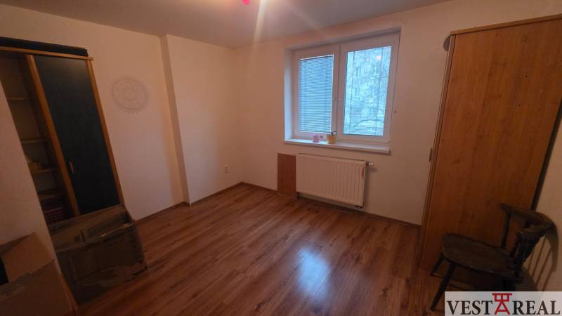 A room in a 3-room apartment features a floor with a wooden decor, wardrobes, and a window with a radiator.