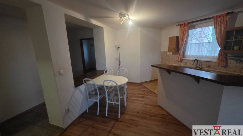 Dining area in a 3-room apartment with a wooden-patterned floor and a white table.