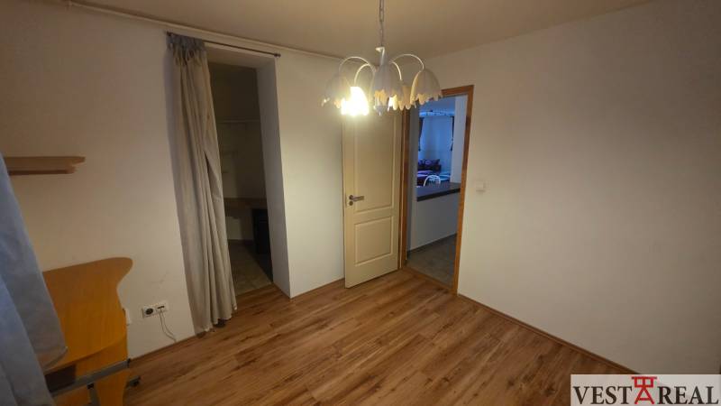 A room with a wooden decor floor, a wardrobe, and a curtain in a 3-room apartment.