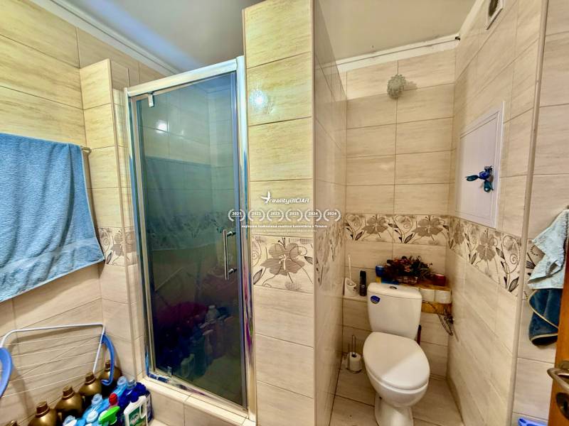 Bathroom in a 2-room apartment with tiles, a shower, and a toilet.