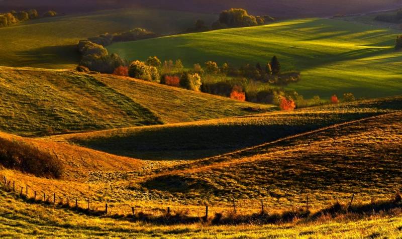 Hilly landscape in the Vráble area with agricultural and forest lands at dusk.