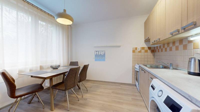 Kitchen in a 2-room apartment with a table and chairs, floor with wooden decor.