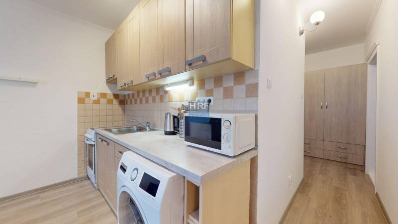 A kitchen in a 2-room apartment with a wooden decor floor and a kitchen unit.