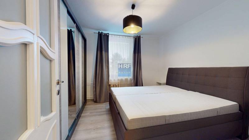Bedroom with a large bed, wardrobe, and wooden decor flooring in a 2-room apartment.