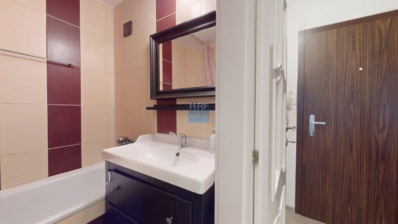 Bathroom with a shower and a sink in a 2-room apartment, tiles in beige and burgundy.