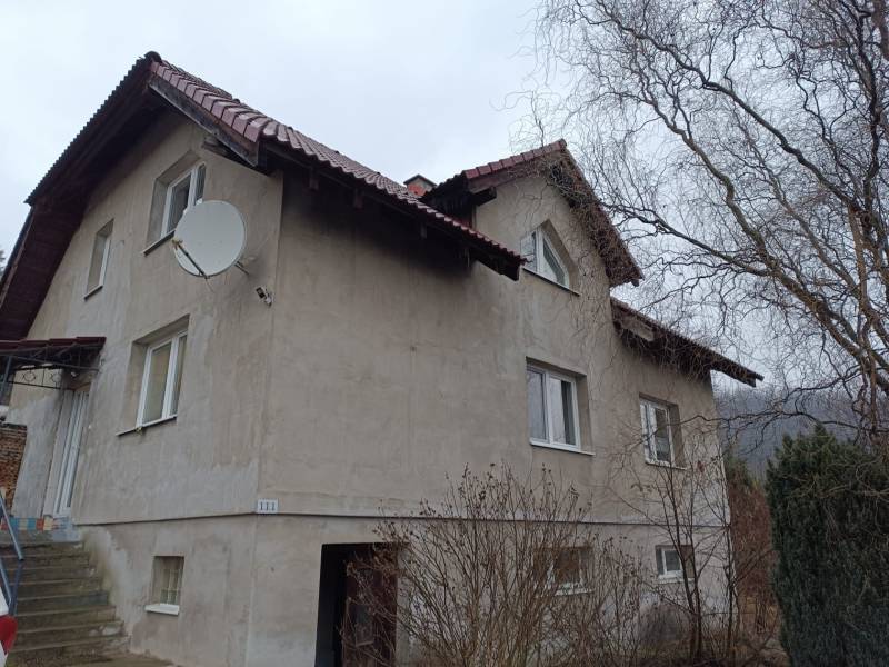 A family house in Orovnica with a light facade, a satellite dish, and a sloped roof.