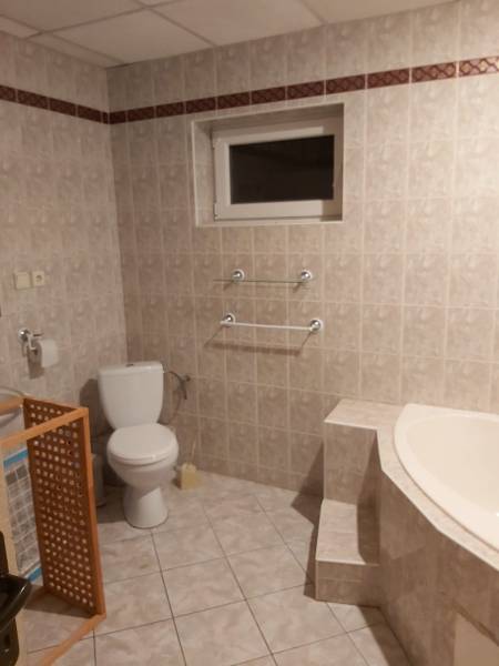 A bathroom in a family house with a bathtub, toilet, and tiles in neutral tones.