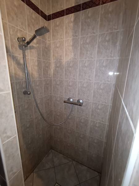 Shower corner with ceramic tiles in a family house, without a tray.