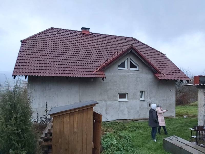 A family house in Orovnica, gable roof, two people on the lawn.